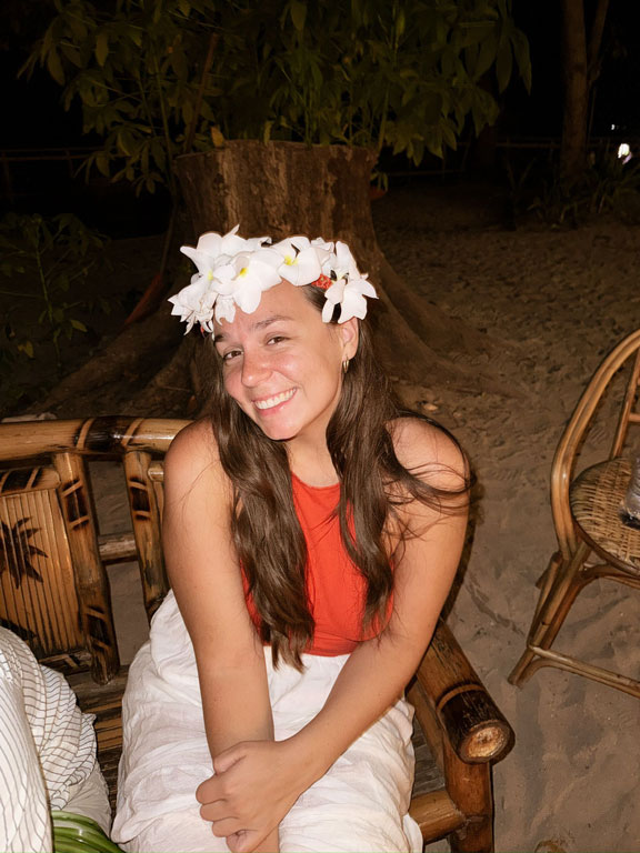 Smiling woman wearing a white flower crown at a tropical beach bar